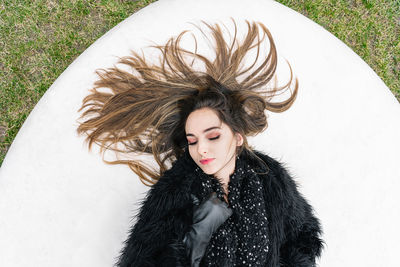 Beautiful young woman standing against white wall