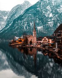 Church by lake against mountain during winter