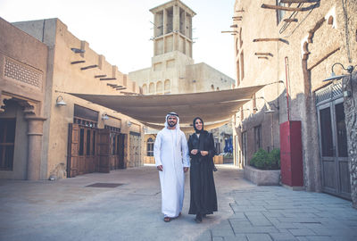 Full length of smiling couple talking while walking on street in town