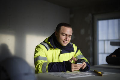 Male engineer at building site using cell phone