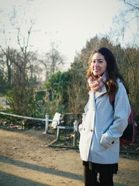 Young woman standing by trees