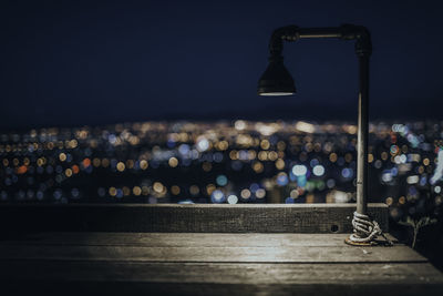 Close-up of illuminated street light against city at night