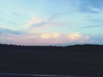 Scenic view of silhouette field against sky at sunset