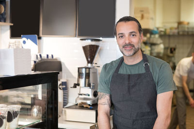 Portrait of confident mature male owner standing at bakery