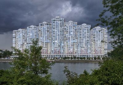 Buildings by river against sky