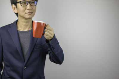 Low angle view of man holding coffee cup against wall