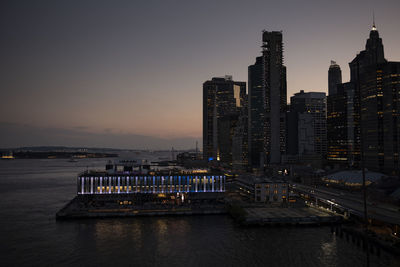 Illuminated buildings in city at sunset