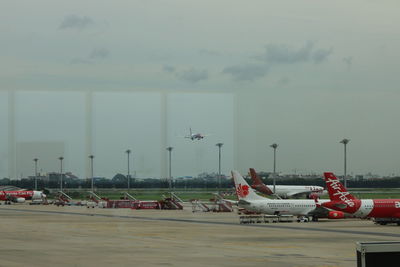 Airplane flying over airport runway against sky