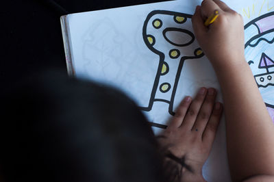 Cropped hand of girl drawing on paper