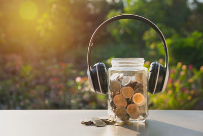 Close-up of coins in jar with headphones on table
