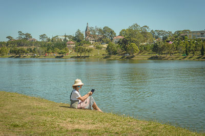 People sitting by lake against sky