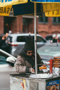 Man using mobile phone on street in city during winter