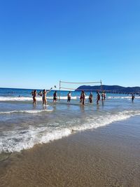 People at beach against clear sky