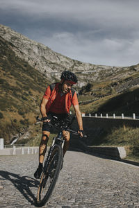 Man cycling on cobbled road at gotthard pass
