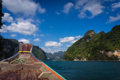 Prow of a ship with beautiful sky, clouds and big mountain.