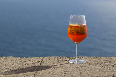 Close-up of wineglass against sea at sunset