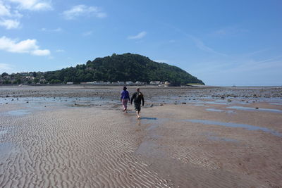 People walking on beach against sky