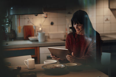 Smiling woman using tablet pc in kitchen