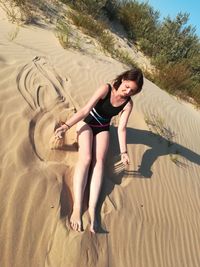 Full length of woman lying on sand at beach