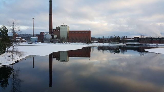 REFLECTION OF FACTORY ON SNOW COVERED LANDSCAPE