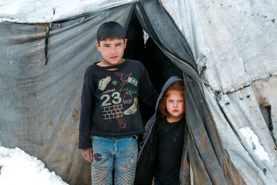 A syrian refugee child at the door of his snow covered tent