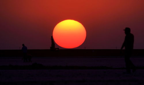 Silhouette man standing against orange sky