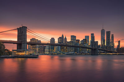 Brooklyn bridge over river with buildings in background during sunset