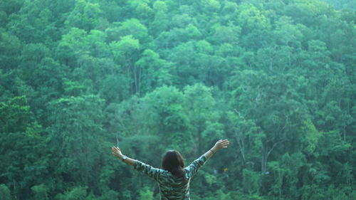 Rear view of person standing by plants in forest