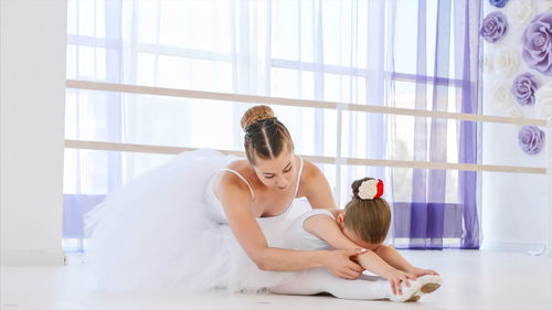 Teacher teaching ballet dancing to cute girl