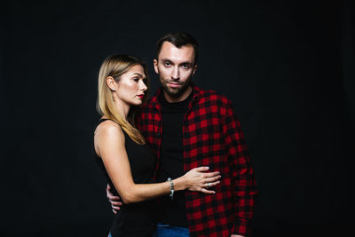 Young couple standing against black background