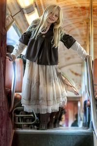 Portrait of playful girl balancing on railing in train