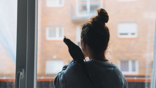 Rear view of woman standing by window