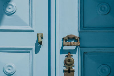 Close up of a metal door knockers on a wooden front door of a traditional house in mykonos, greece.