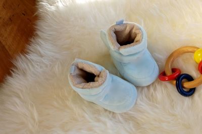 High angle view of baby booties by toy on fur