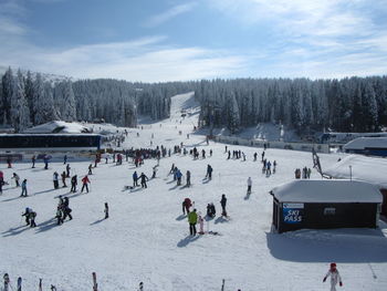 People on snow covered landscape against sky