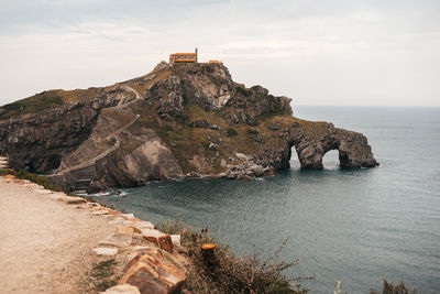 Scenic view of sea by cliff against sky