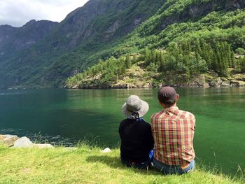 Rear view of woman sitting on lakeshore