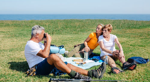 Senior father taking a photo to his family with duck face sitting on a blanket having picnic