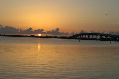 Silhouette bridge over river against sky during sunset