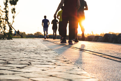 Rear view of people walking on footpath at sunset