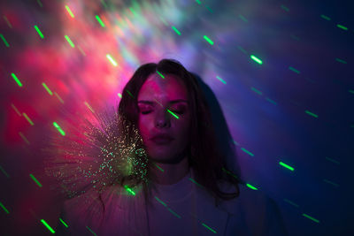 Beautiful woman standing against illuminated light