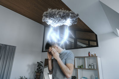 Young man holding camera while standing at home