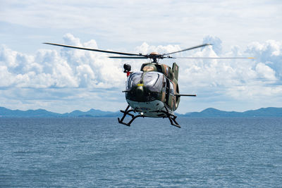 Helicopter flying over sea against sky