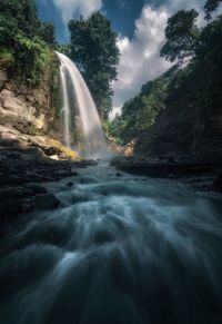 Scenic view of waterfall against sky