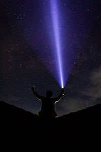 Rear view of silhouette man standing against sky at night