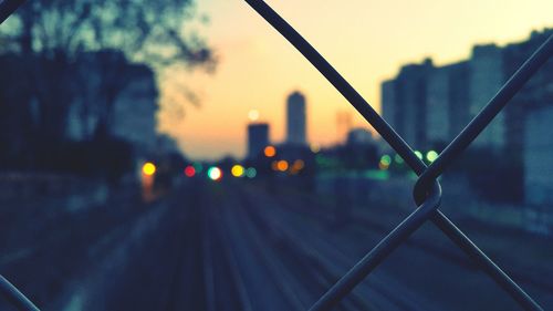 Railroad tracks during sunset seen through fence