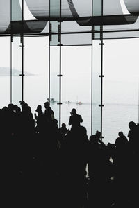 Silhouette people in sea against sky