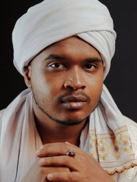 Portrait of young man wearing hat against black background