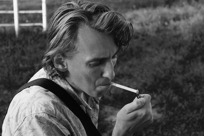 High angle view of young man igniting cigarette on field