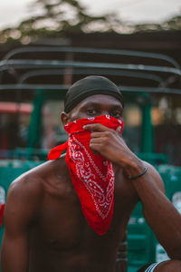 A young adult with a red bandana sitting in a garage 